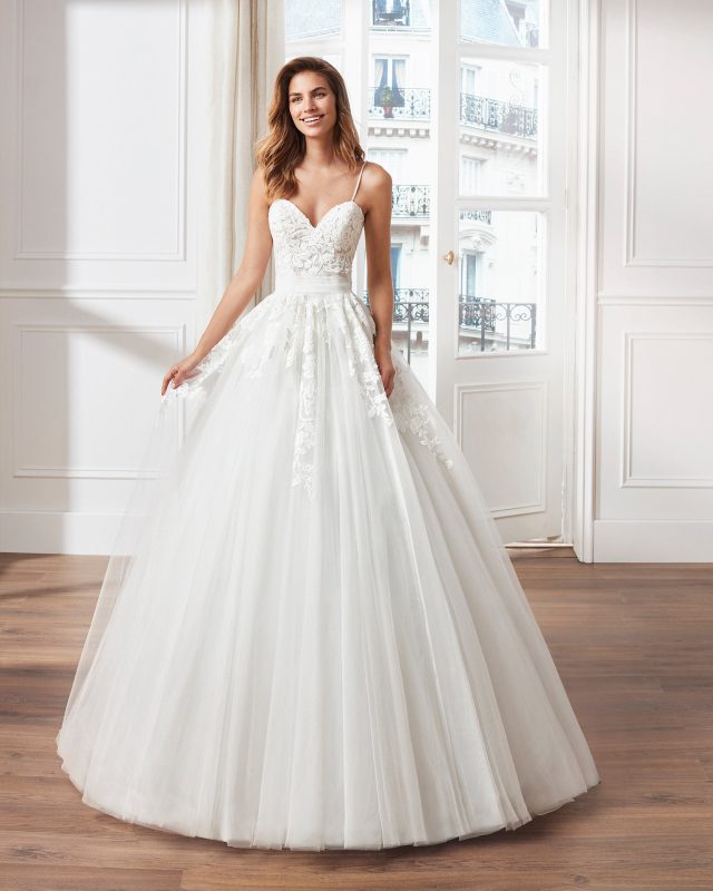 Frau im weißen Hochzeitskleid an großem Fenster